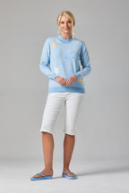 Buy Online Petula Pullover Alice Collins -  Woman wearing a light blue striped sweater and white pants on a gray background