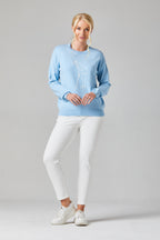 Buy Online Lady Golfer Pullover Alice Collins Woman wearing a light blue sweater with a design and white pants on a gray background