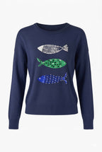 A navy blue crewneck sweater featuring three stylized fish motifs on the front chest, with one white fish, one green spotted fish, and one blue spotted fish, shown against a plain white background.